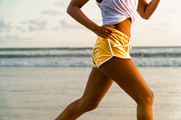 Fit young woman jogging on the beach. Sea shore running workout outdoor. Bright sports wear,...