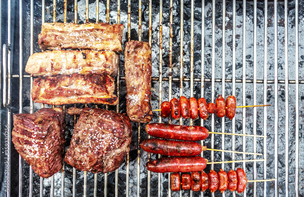 Wall mural Traditional argentinian food barbeque (asado) grilled with a lot of beef, pork, achuras and red bell peppers with eggs.