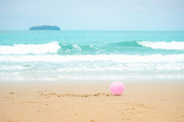 Fototapeta na wymiar Pink ball on sandy summer beach with blue sea, playing and having fun with sandat on tropical beach