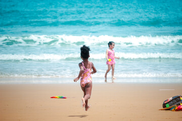 Little cute kid girl  having fun on sandy summer with blue sea, happy childhood friend running and  playing on tropical beach