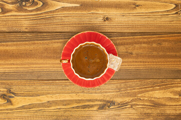 Plenty of sparkling classic Turkish Coffee in a red cup with a Turkish delight top view beside it.