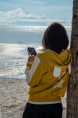 Girl at beach using mobile phone
