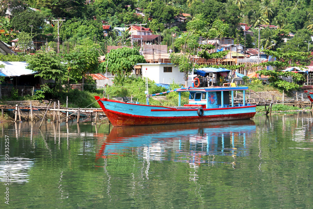 Wall mural Colorful blue and red fishing boats in the Batang Arau river and port in Padang City in West Sumatra, Indonesia.