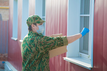 the military delivers food to your home. assistance to pensioners, the poor and the population. a courier in rubber gloves holds a box