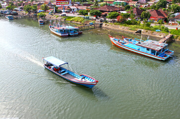 Colorful blue and red fishing boats in the Batang Arau river and port in Padang City in West Sumatra, Indonesia.