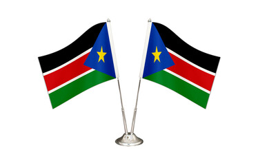 South Sudan table flag isolated on white ground. Two flag poles with flags and South Sudan flag on the table.