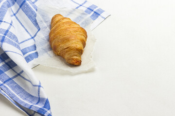 Croissant on white and blue checkered napkin.