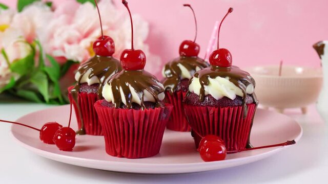 Red velvet cupcakes with chocolate sauce and cherries for dessert, parties and holiday celebrations. Dolly shot.