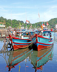 Colorful blue and red fishing boats in the Batang Arau river and port in Padang City in West Sumatra, Indonesia.