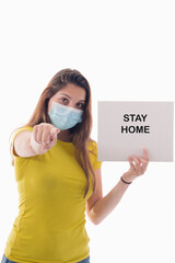 Young female using a surgical mask holding a sign with a message and pointing at the camera