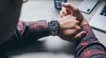fashionable wearing stylish looking at luxury watch on hand check the time at workplace.concept for...
