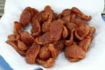 Pile of deep fried cutting Chinese pork sausage on the food oil absorption paper (Oil blotting paper). Famous local crispy pork sausage in Asia street food. 