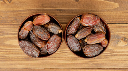 Date dates in wooden bowls on wooden floor.