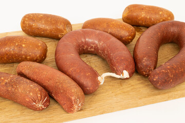 Presentation of sausage salami and bacon on a cutting board on a white background.