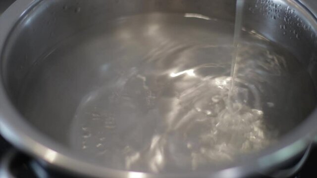 Pouring cooking oil in a pot preparing meal. Kitchen.