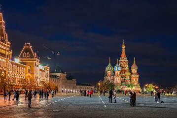 Night view of Saint Basil's Cathedral and GUM, luxury shopping center in Red Square with people walking in Moscow Russia