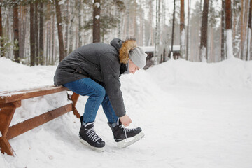 Young man sitting on a bench in winter park.