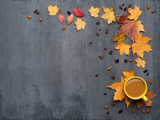 Seasonal autumn background. Frame of colorful maple leaves and a cup of hot drink, coffee, latte or cappuccino, nutmeg and cinnamon over grey.