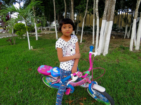 ni&ntilde;a en bicicleta tocando su codo para aliviar dolor de caida 