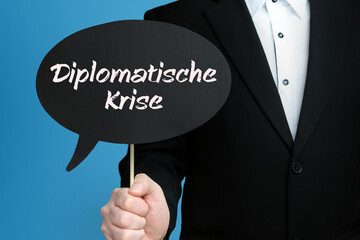 Diplomatische Krise. Mann im Anzug hält Sprechblase in der Hand. Der Text Diplomatische Krise steht im Schild. Blauer Hintergrund. Geschäftsmann für Business, Finanzen, Statistik