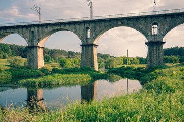 Fototapeta na wymiar Old Arched Stone Railroad Viaduct Bridge over the river. Novohrad-Volynskyi city, Ukraine, Europe
