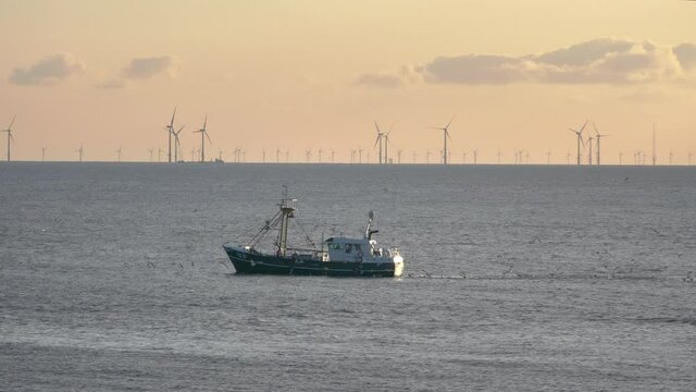 Fishing boat on the north see coast with wind turbines on the background