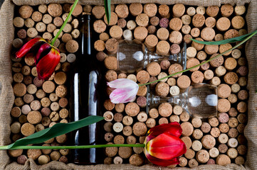 Wine corks of different sizes, a corkscrew, a bottle of wine and a glass shot on an old wooden...