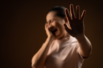 Asian woman scared screaming covering face by her hands standing isolated on beige background.