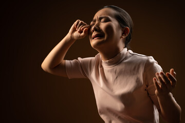 Asian woman sad and crying standing isolated on beige background.