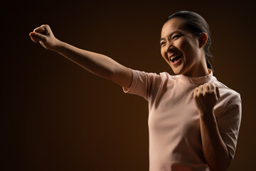 Asian woman happy confident standing showing her fist make a winning gesture isolated on beige background.