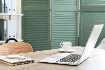 Modern laptop at workplace in room