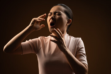 Asian woman was sick with sore throat standing isolated on beige background.