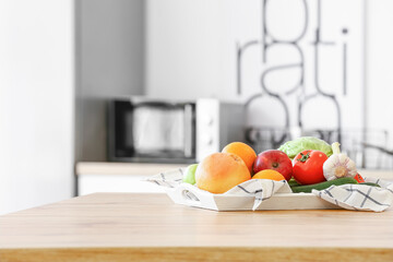 Tray with fresh fruits and vegetables on kitchen table