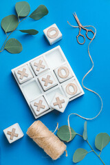 Scissors with threads and noughts-and-crosses game on color background