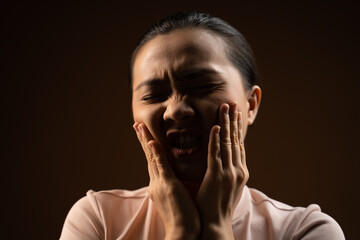 Asian woman was sick with toothache standing isolated on beige background.