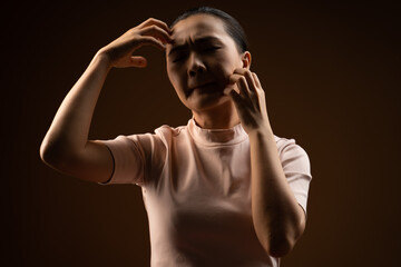 Asian woman scratching her head, standing isolated on beige background.