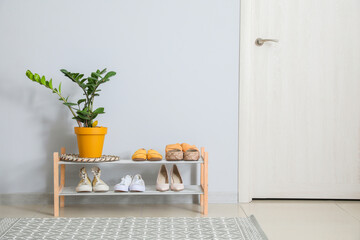 Stand with stylish shoes in interior of modern hall