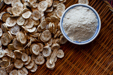 Dried banana slices  With raw banana powder in a cup  Raw banana powder is an ancient medicine used for gastritis treatment.  All laid on a wooden floor
