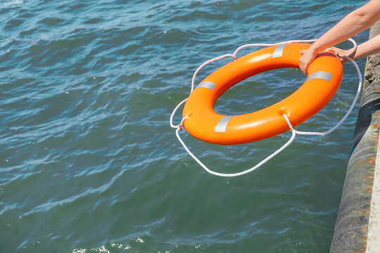 Woman throwing lifebuoy ring on water