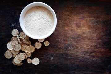Dried banana slices  With raw banana powder in a cup  Raw banana powder is an ancient medicine used for gastritis treatment.  All laid on a wooden floor
