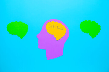 Paper human head with word DYSLEXIA on color background