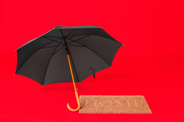 Stylish umbrella and door mat on color background