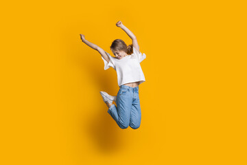 Happy caucasian woman jumping on a yellow studio wall gesturing happiness
