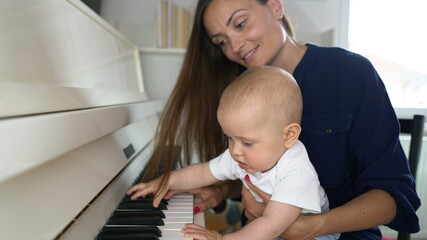 A cute mommy playing a white piano with her baby boy