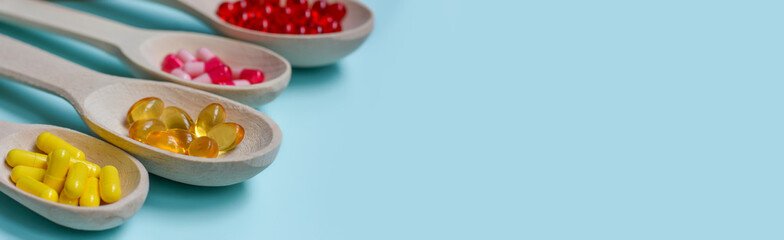Four wooden spoons full of pills, vitamins, capsules, omega-3 fish oil,vitamin E, medicines and...