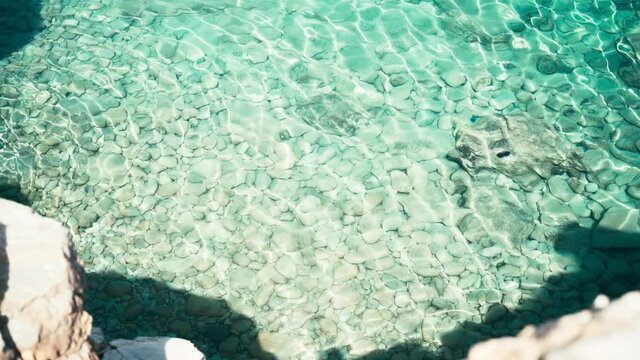 Transparent turquoise blue sea water in the bay, top view. Sun glare . High quality 4k footage