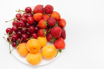 Assorted fruits in white bowl isolated on white background. Bowl of healthy fresh fruit. Top view. Strawberry, cherry, apricot. High quality photo