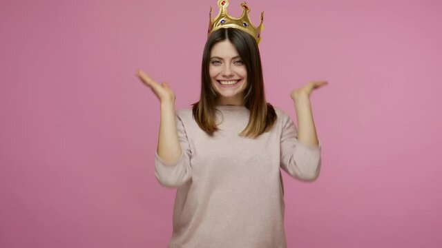 Look at queen! Attractive egoistic brunette woman wearing golden crown, feeling confident arrogant, proud of her beauty and success, self-loving concept. indoor studio shot isolated on pink background