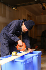 European handyman cutting wood with jigsaw on construction site.