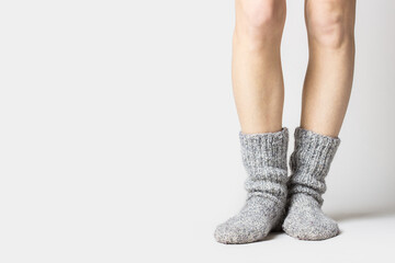 Woman is standing in warm gray socks on a light background. Only legs visible. Banner